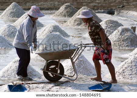 SAMUTSONGKRAM, THAILAND - MARCH 14: women work at a salt farm on March 14, 2010 in Samutsongkram, Thailand. Samutsongkram is a big salt production area of Thailand.