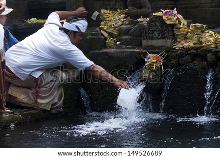 BALI, INDONESIA - MAY 6: a man collects the holy water in bottle at the Tirta Empul Temple on May 6, 2013 in Bali, Indonesia. The water is believed to be holy and taken home for use in all ceremonies.