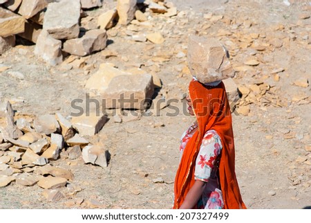 JAISALMER, INDIA - FEB 25: A woman carries a brick on her head on a construction site on Feb 25, 2013 in Jaisalmer, India. Construction is the third-largest employer of women in India