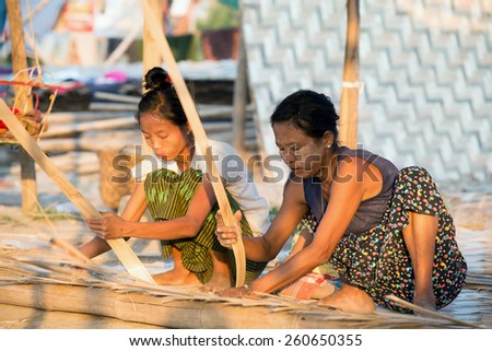 MANDALAY, MYANMAR - MAR 6:  Local women are making bamboo panels on Mar 6, 2015 in Mandalay, Myanmar.  Bamboo logs are shredded into thin strips and cross-oriented and to be used as wall, roof or mat.