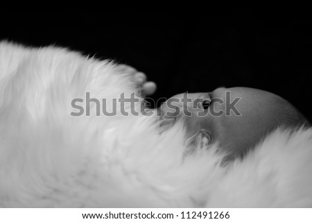 New born baby lying and covered by white fur in black and white