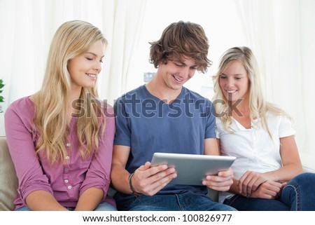 Friends sit together on the couch as they all look at a tablet pc