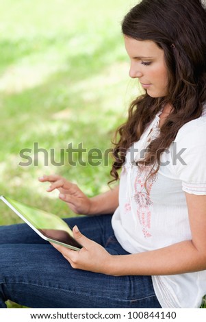 Young attractive woman sitting in a public garden while using her tablet computer