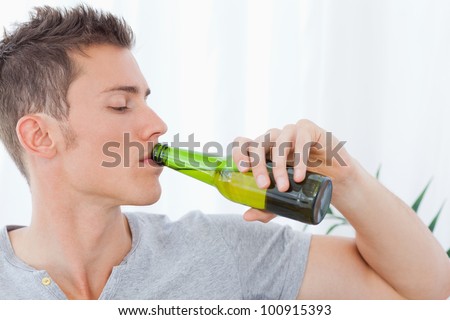 An attractive man drinking beer while looking at the bottle