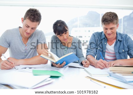 Three students sit together as they all study their homework