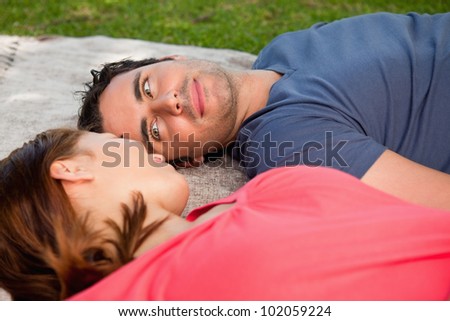 Man looking into his female friends eyes while lying on a grey quilt