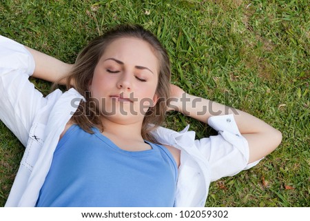 Young relaxed girl napping in a parkland with her hands behind her head