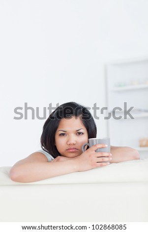 Woman holding a mug while resting on a couch in a living room