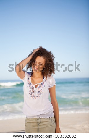 Young woman standing upright with her hand on her head in front of the sea