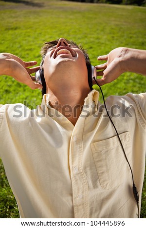 Man singing while using headphones to listen to music as he is sitting in grass