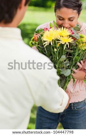 Woman smelling the bouquet of aromatic flowers which has been presented to her by a friend