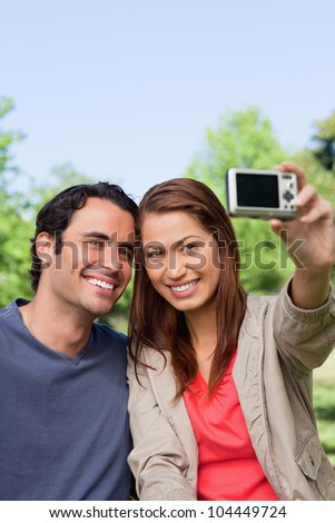 Woman and her friend looking towards her camera for a picture of them to be taken in a grassland area