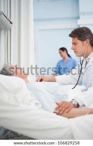 Doctor auscultating a patient with a stethoscope in hospital ward