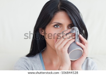 Woman drinking from a mug that she holds with hands in a living room