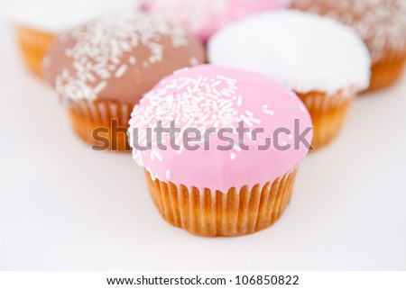 Close up on a pyramid of muffins with icing sugar against a white background