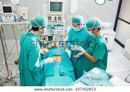 High angle view of surgeon operating an uncounscious patient in an operating theater