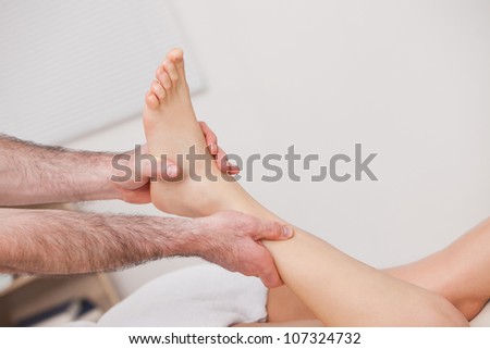Podiatrist manipulating the ankle of his patient while holding it indoors