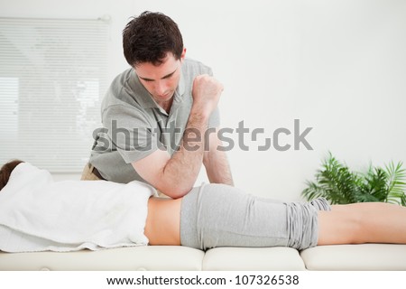 Man pressing the back of a woman with his elbow in a room