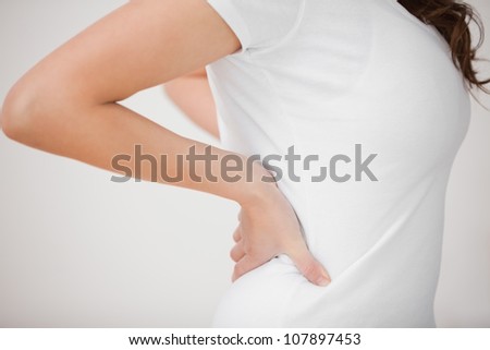 Woman putting her hands on her back indoors