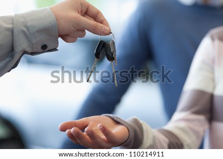 Car dealer giving keys to a customer in a car shop