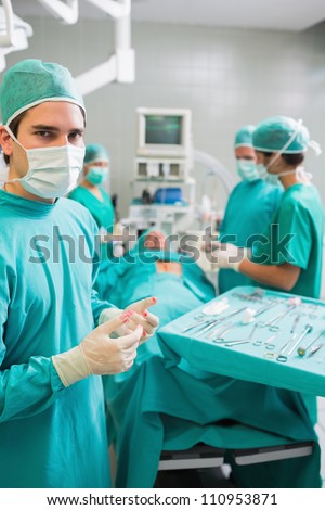 Surgeon wearing gloves with blood next to a patient in an operating theater