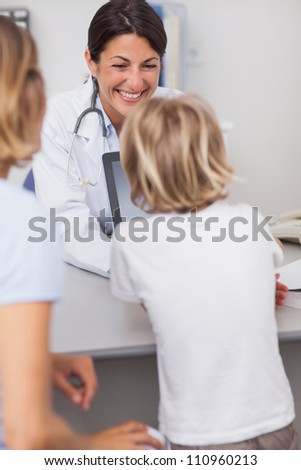 Smiling doctor presenting a tablet computer to a child in hospital ward
