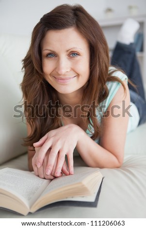 Woman lying on the belly on a sofa looking at camera in a living room