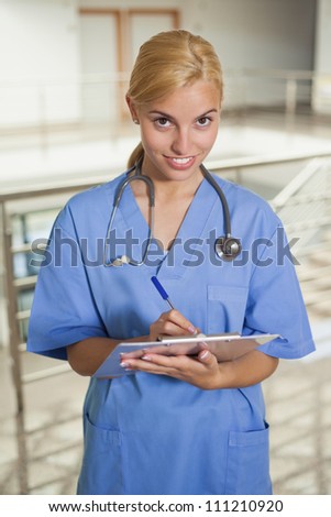Nurse writing on a clipboard in hospital hallway