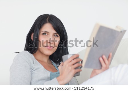 Woman holding a grey mug and a book in a living room
