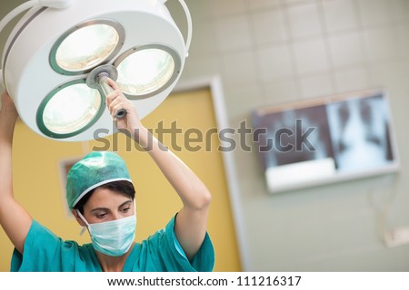 Woman holding a surgical light in a surgical room