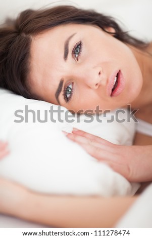 Brunette woman lying while placing her head on a pillow in her bedroom