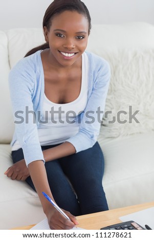 Black woman smiling while sitting on a sofa in a living room