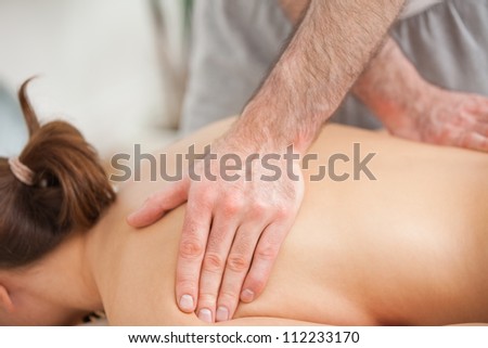 Woman lying on the belly while being massaged on his back in a room