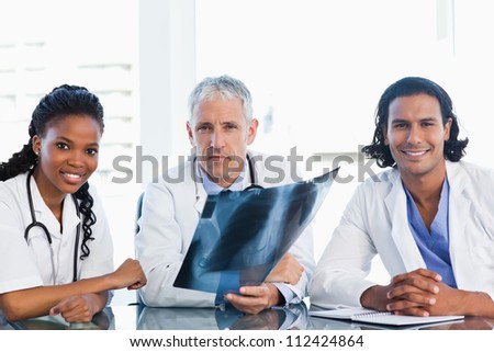 Mature doctor with smiling colleagues looking at an x-ray scan of lungs
