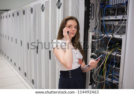 Brunette calling while checking servers with tablet pc in data center