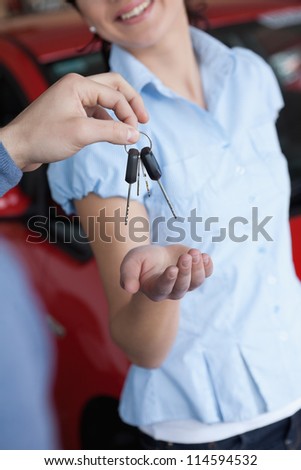 Smiling woman getting car keys in a car shop