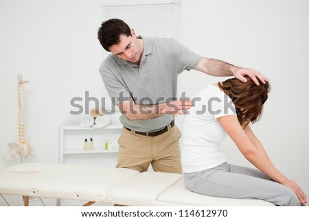 Physiotherapist looking at the spinal column of a woman in a medical room