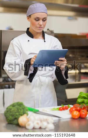 Chef consulting digital tablet beside vegetables in the kitchen