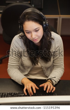 Woman sitting in front of the computer wearing headphones in college computer