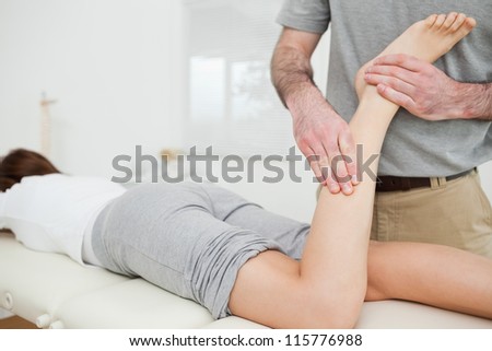 Woman lying while a doctor is examining her leg in a room