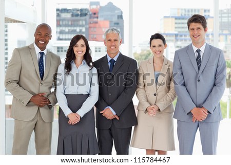 Business team smiling and standing upright side by side with their hands crossed