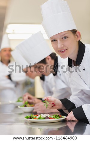 Smiling chef looking up from preparing salad in culinary class