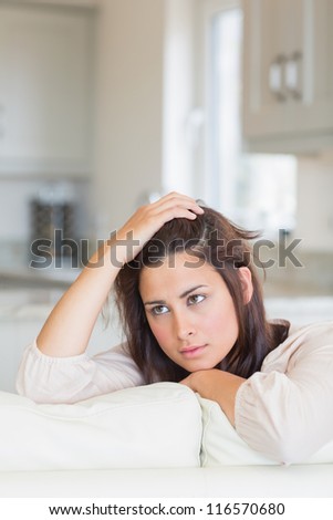 Woman thinking and sitting on couch with hand on head