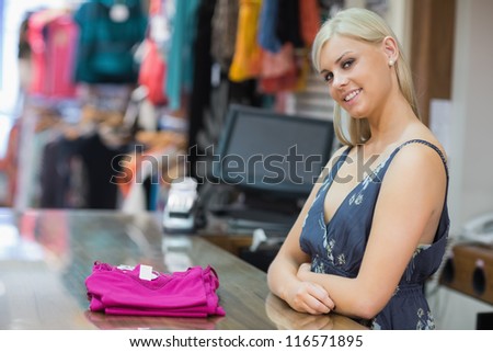Woman standing behind the counter smiling with clothes folded on the counter