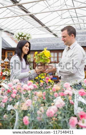 Happy couple holding up yellow flower in garden center