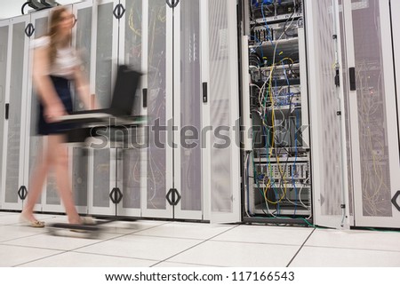 Woman pushing computer through data center beside the servers
