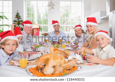 Smiling family around the dinner table at christmas wearing santa hats
