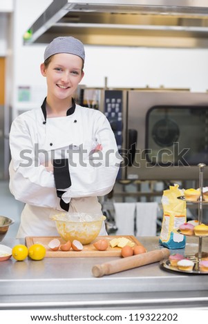 Smiling pastry chef standing behind counter in kitchen