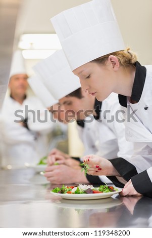 Chef\'s applying finishing touches to salads as head chef is watching