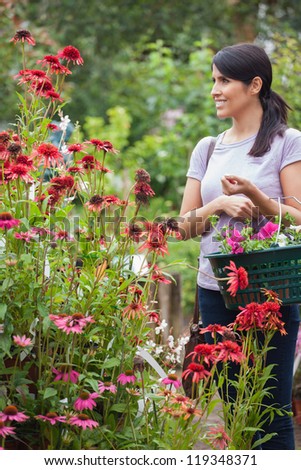 Customer holding a basket while smiling in garden center